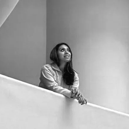 Camila Gomez, founder of CUBIQA, leaning on a curved white balcony